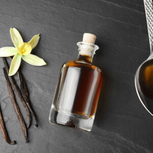 Flat lay composition with vanilla extract on black table