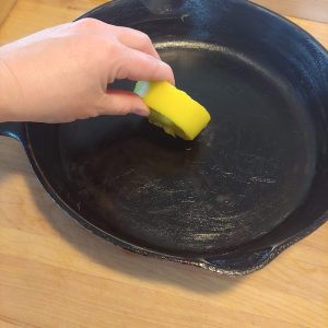 applying a beeswax cast iron conditioning bar to cast iron pan