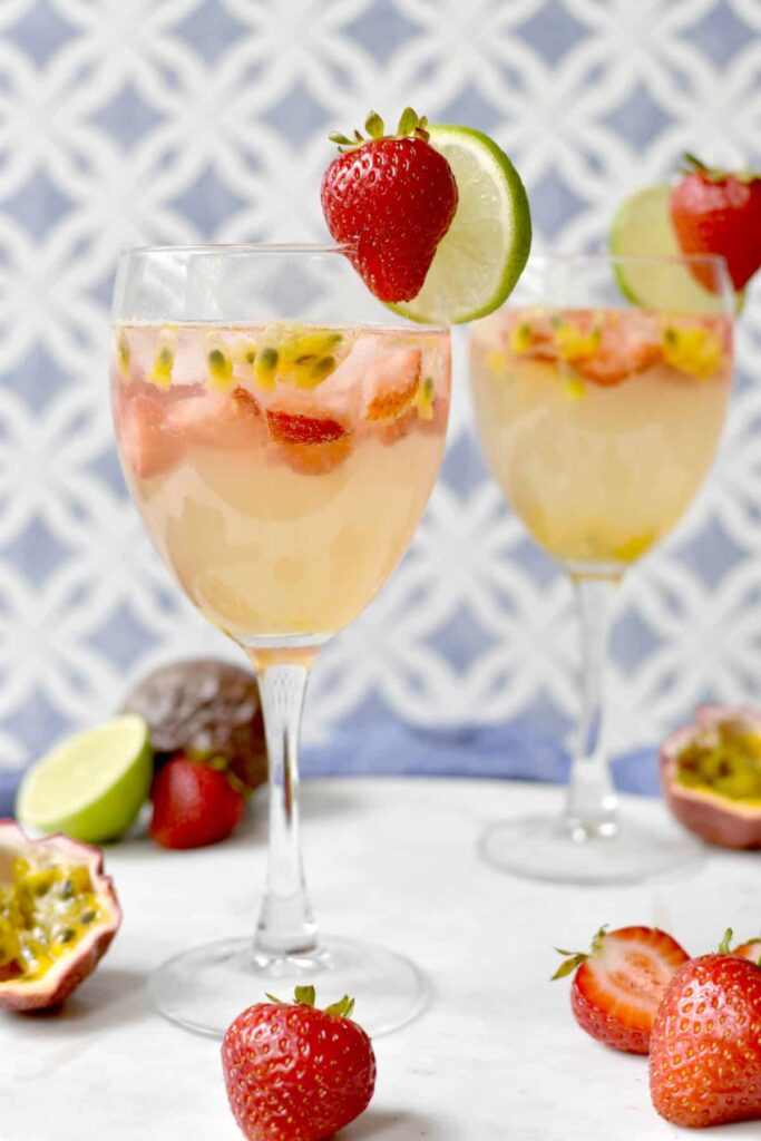 wo cups of drink made with coconut water, sparkling water, strawberry pieces, passion fruit pulp, and lime juice. Lime slice and strawberry garnishing each cup