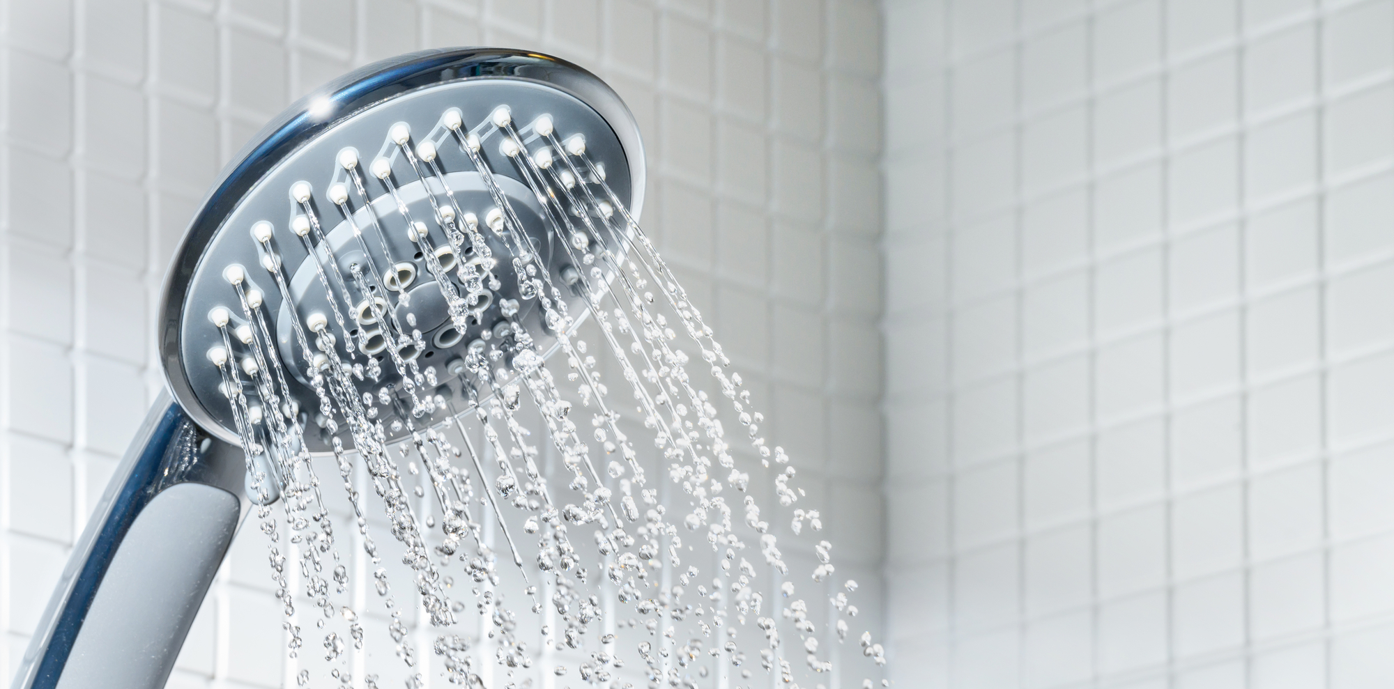 Modern blue Shower head with running water in white bathroom. Copy space