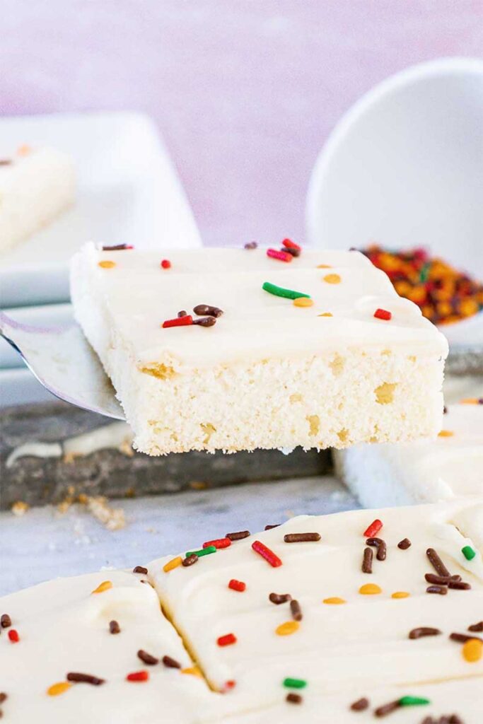 a spatula lifting a freshly sliced maple frosted sugar cookie bar out of the baking dish