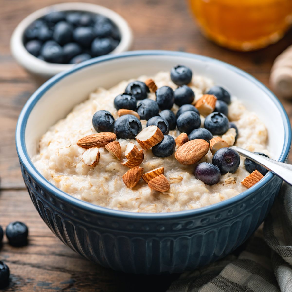 a bowl of oatmeal with blueberries and almonds on a wooden table