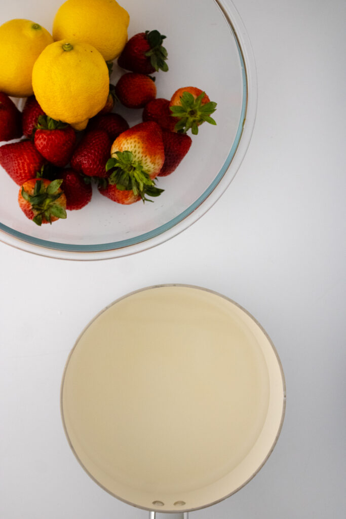 a bowl of strawberries and lemons and a sauce pan
