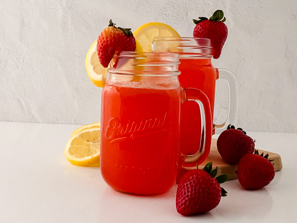 two pitcher of strawberry lemonade with sliced fruits at the mouth