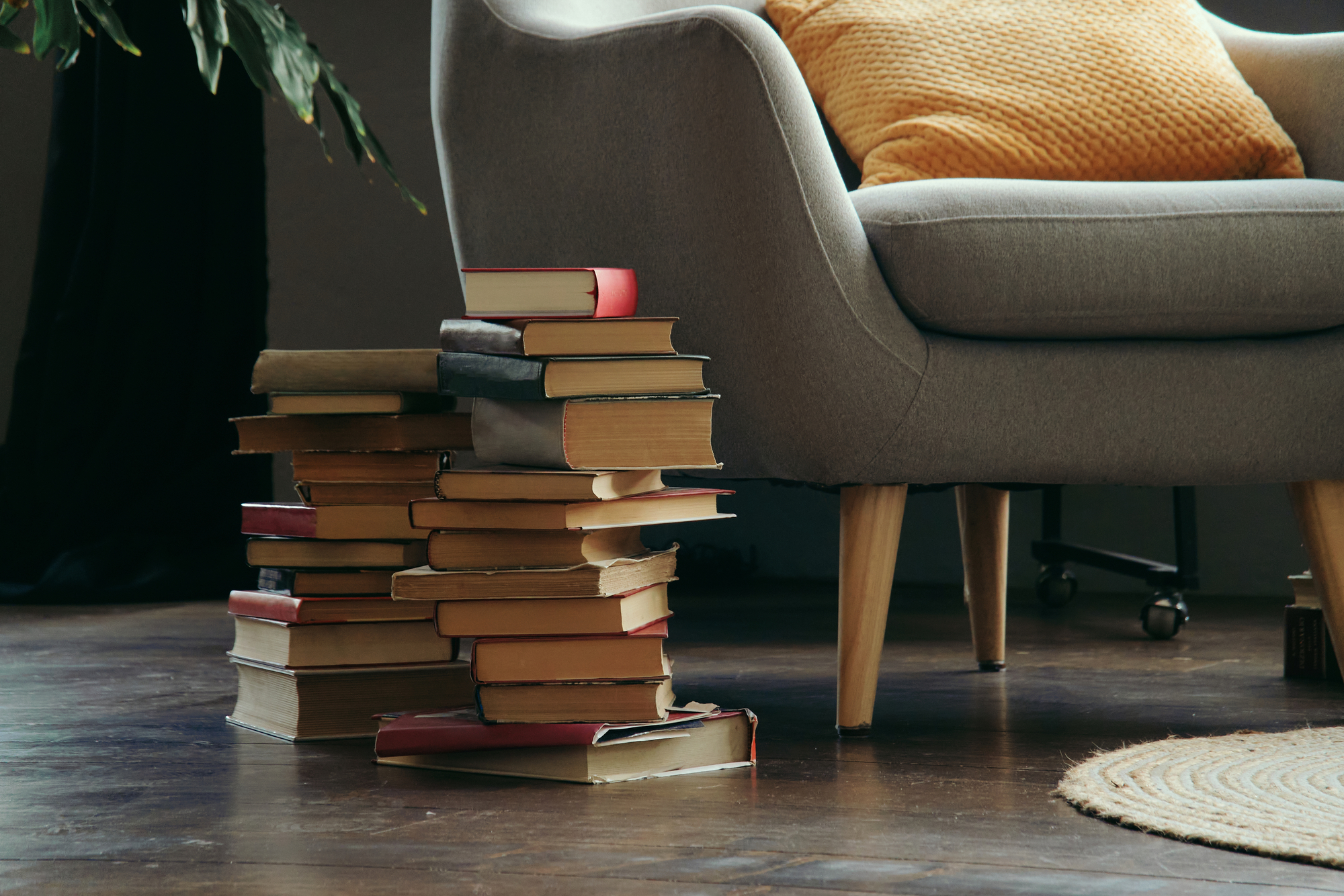 Old books next to the reading chair are stacked on the floor