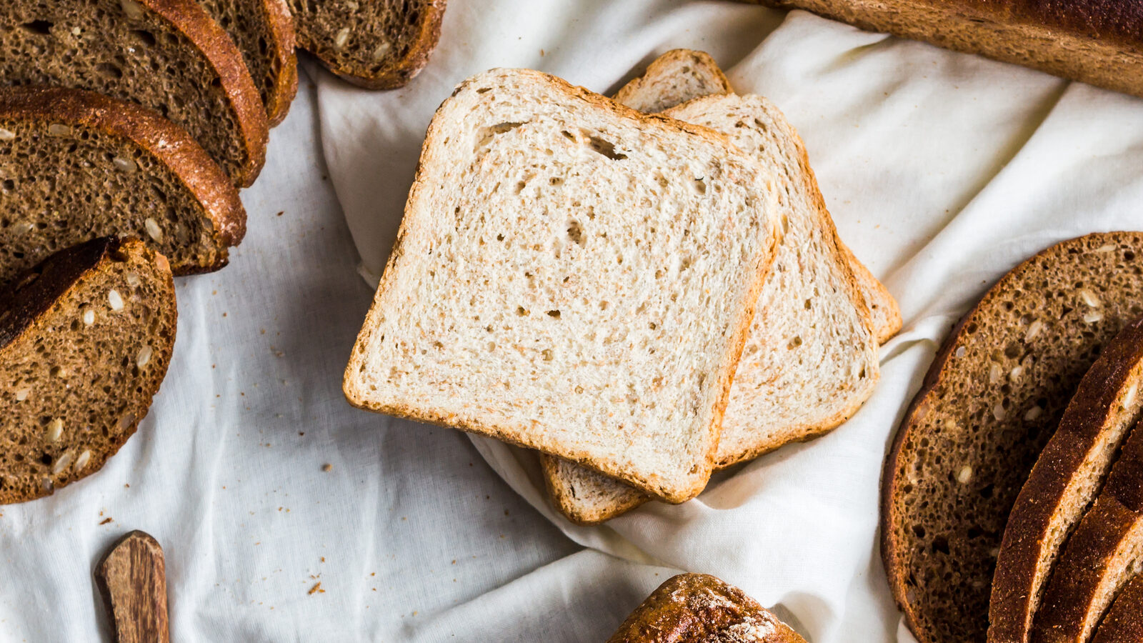 28 Ways to Live Sustainably and Reduce Dependence on Retail and Grocery Stores 8 ssorted bread, slices of rye bread on linen tablecloths, grey wooden background