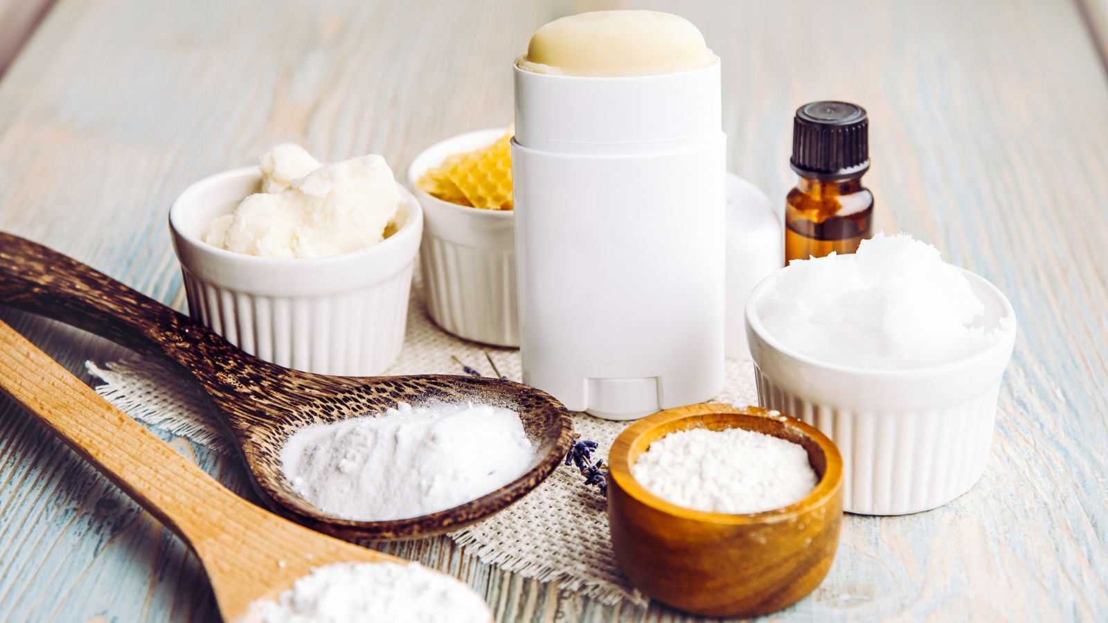 Making homemade deodorant stick with all natural ingredients concept. Wooden background. Ingredients: arrowroot powder, baking soda, beeswax, shea butter, essential oil, cornstarch, coconut oil.
