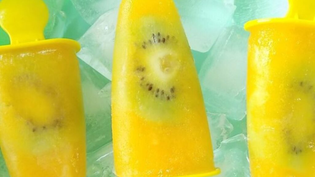 21 Delightful Homemade Popsicle Recipes 14 Orange popsicles with kiwi slices in a bowl that is full of ice cubes.