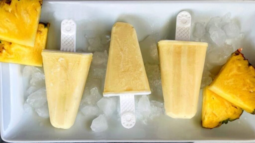 21 Delightful Homemade Popsicle Recipes 7 Pineapple popsicles on a tray of ice.