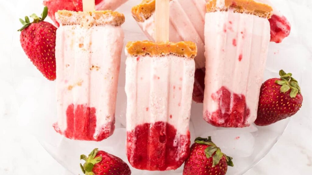 21 Delightful Homemade Popsicle Recipes 9 Plate of strawberry cheesecake popsicles.