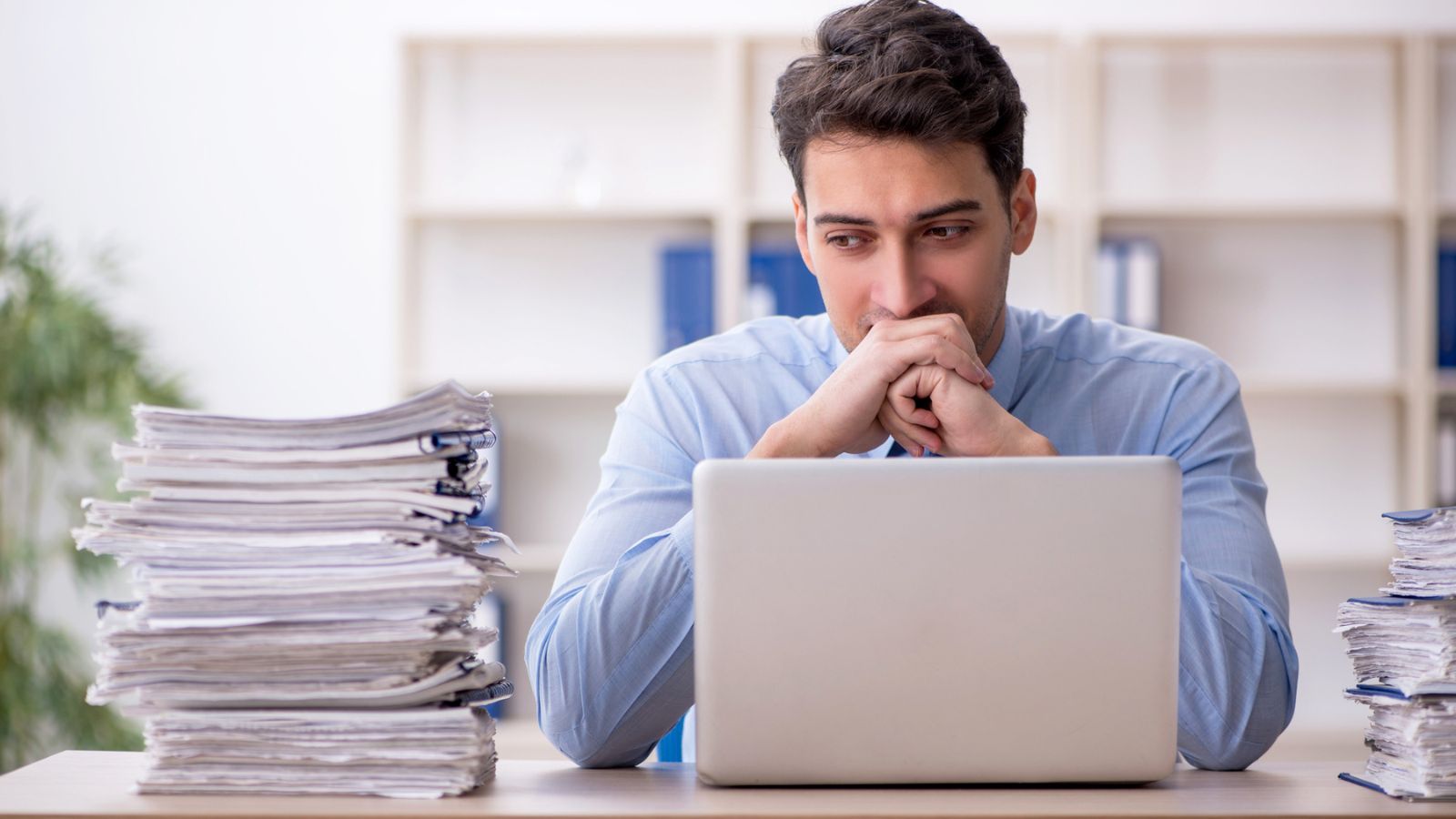 man around laptop looking at paper