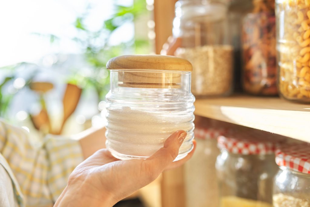 14 Food Storage Rules Every Prepper Should Follow 7 woman holding sugar in front of pantry