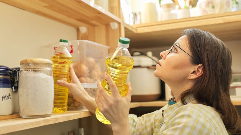 The System I Use to Rotate Food and Avoid Waste in My Stockpile 8 Food storage wooden shelf in pantry with products. Woman taking food sunflower oil for cooking 1200x675