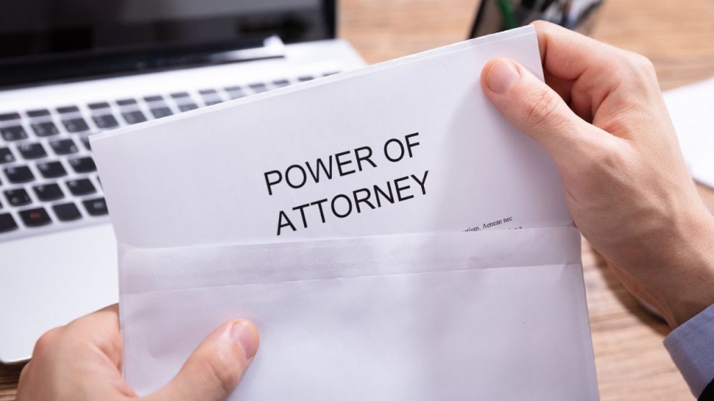 19 Important Documents You Should Never Throw Out 14 A Person's Hand Holding Power Of Attorney Document In White Envelope In Front Of Laptop