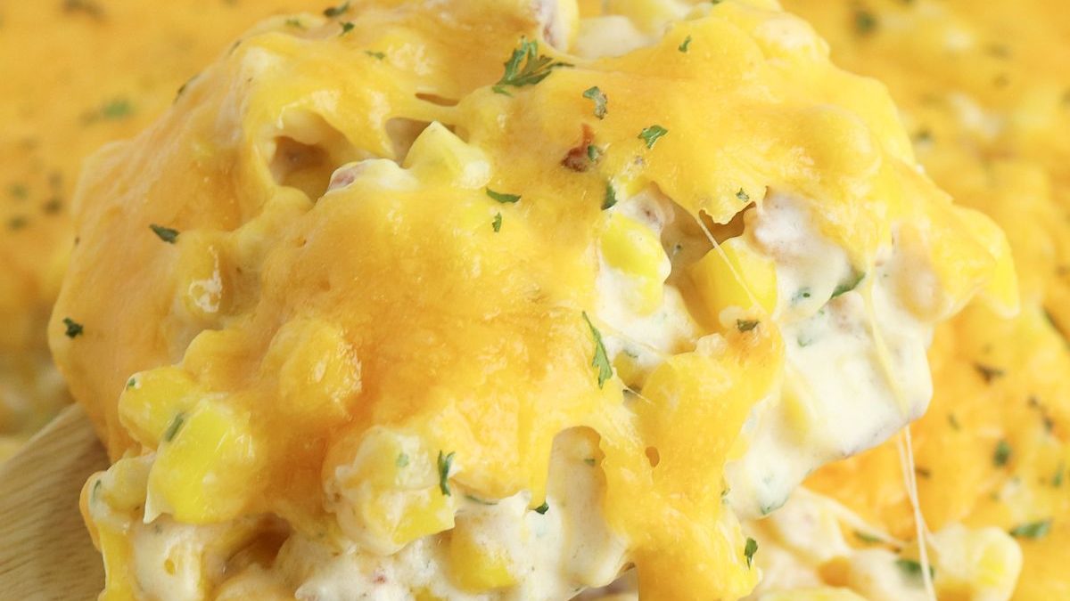 26 Fresh Corn Recipes You'll Wish You Tried Sooner 25 Cheesy corn casserole in a white dish with a wooden spoon.