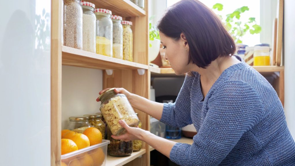 Looking for Cheap Groceries? 13 Best Grocery Stores for Budget Shoppers 15 woman in pantry looking at canned goods
