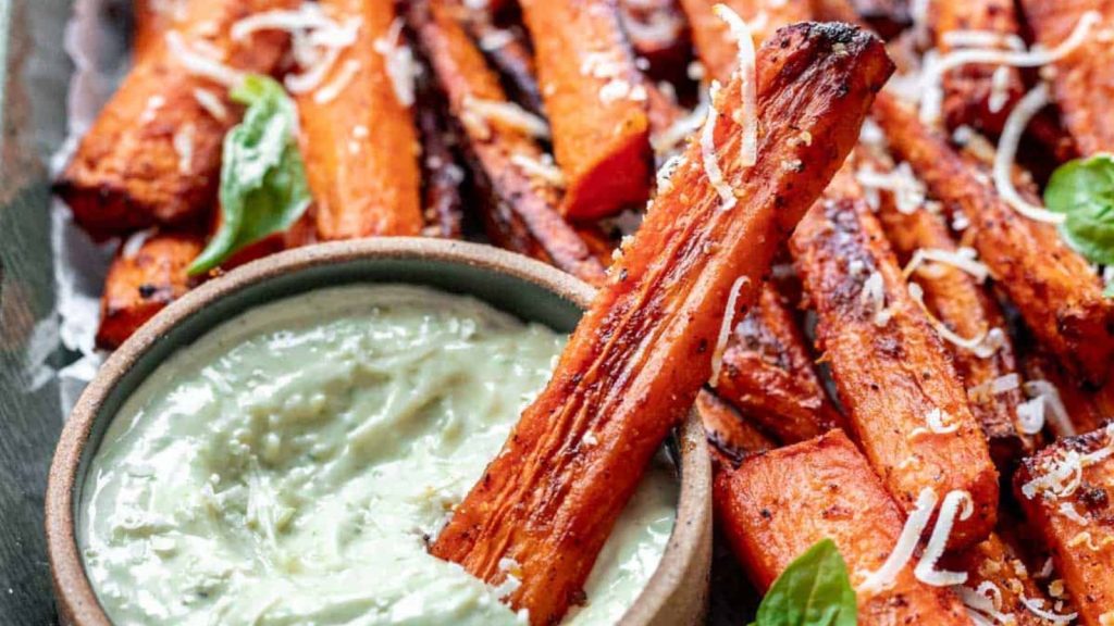 Air fryer carrot fries dipped in pesto aioli in a tray.