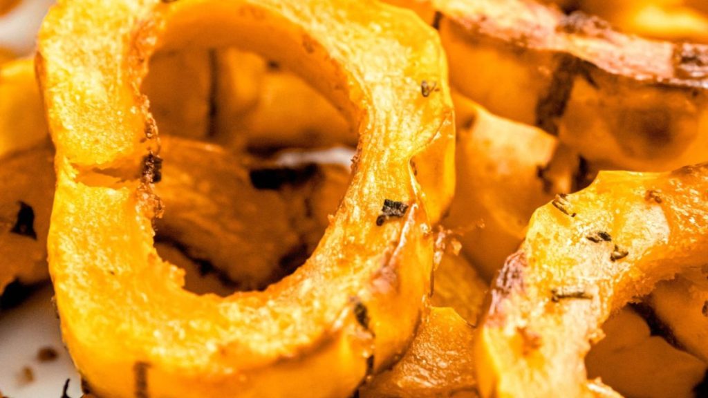 closeup shot of a serving platter of golden brown slices of air fryer delicata squash.