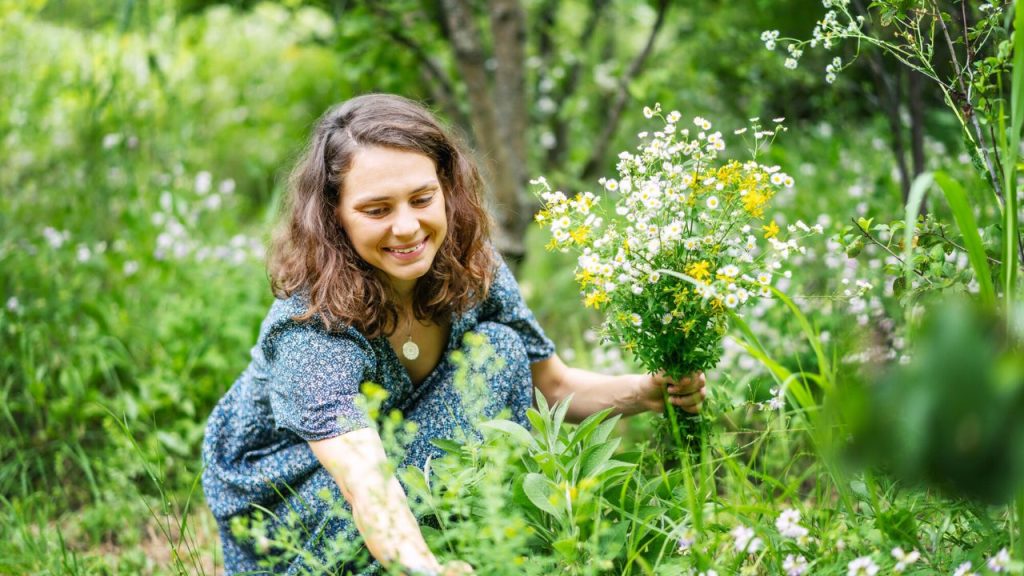 woman picking flowers weeds in garden
