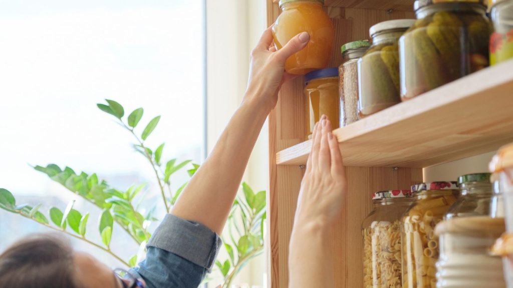 The System I Use to Rotate Food and Avoid Waste in My Stockpile 1 woman stocking pantry