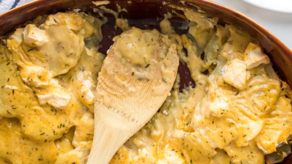 24 Potato Recipes You’ll Never Get Tired Of 20 Dish of cream cheese scalloped potatoes with a wooden spoon in it.