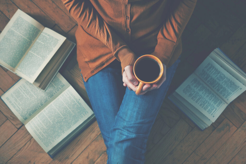 These Cozy, Feel-Good Hobbies Are the Perfect Way to Slow Down and Ease Into the New Year 1 woman with coffee cup reading books